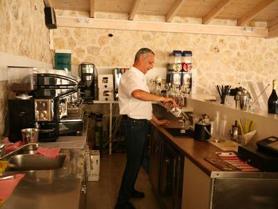 Cuoco prepara cibo in cucina d'hotel con pareti in pietra e soffitto con travi di legno.