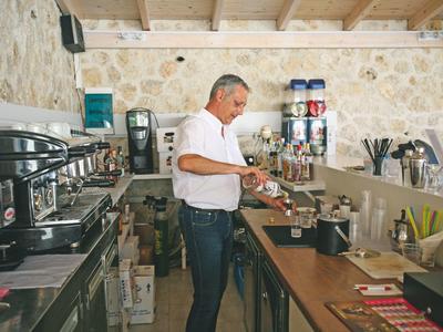 Mężczyzna przygotowujący napoje za ladą w rustykalnej kawiarni.