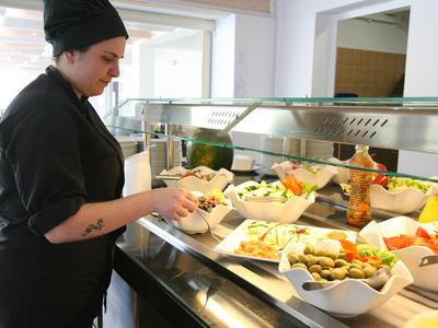 Addetto in abbigliamento nero serve cibo a un buffet in un ristorante di un hotel.