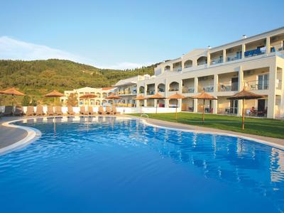 Complexe hôtelier moderne avec une grande piscine et vue sur les collines boisées.