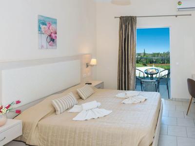 Chambre d'hôtel lumineuse avec lit double, balcon et vue sur le jardin.