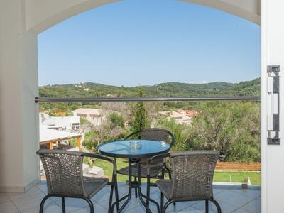 Balcon avec deux chaises et table en verre donnant sur le paysage et le ciel.