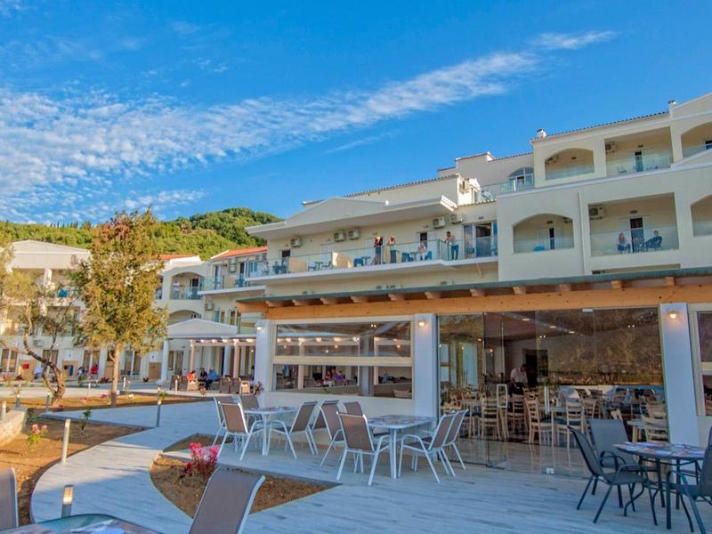 Jasny pokój hotelowy z podwójnym łóżkiem, biurkiem, telewizorem płaskoekranowym i zasłonami na oknach.