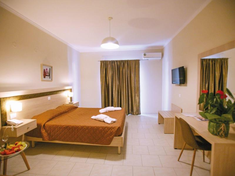 Jasny pokój hotelowy z podwójnym łóżkiem, biurkiem, telewizorem płaskoekranowym i zasłonami na oknach.