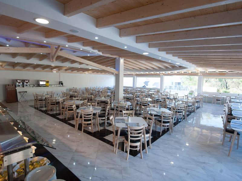 Taras z stołami i parasolami przed hotelem na wzgórzach.