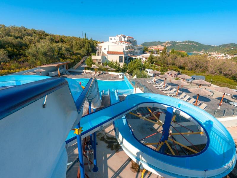 Park wodny z niebieskimi zjeżdżalniami i parasolami w słonecznym krajobrazie