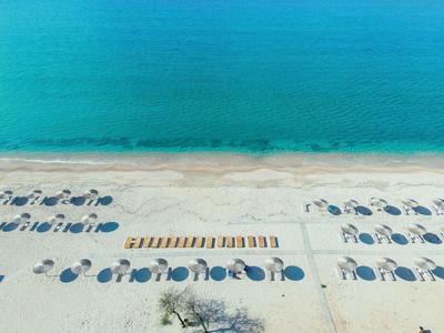 Luchtfoto van een turquoise zee met een zandstrand en georganiseerde rijen blauwe parasols en ligbedden.