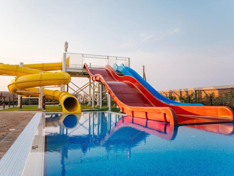 Kleurige glijbanen komen uit in een helder blauw zwembad bij een waterpark.