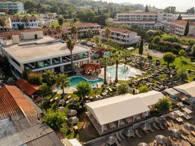 Übersichtliches Resort mit Pool, Sonnenliegen, Palmen und mehreren Gebäuden in sonniger Lage.