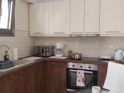 Cuisine moderne avec placards inférieurs en bois, placards supérieurs clairs et four encastré.