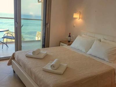 Chambre moderne avec vue sur la mer, lit double et balcon avec table et chaises.