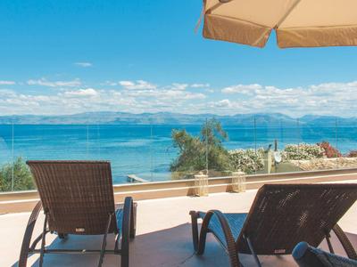 Zwei Liegestühle auf einer Terrasse mit Blick auf das Meer und bewölkten Himmel.