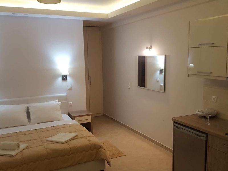 Chambre d'hôtel simplement meublée avec lit double, tables de chevet et éclairage mural.