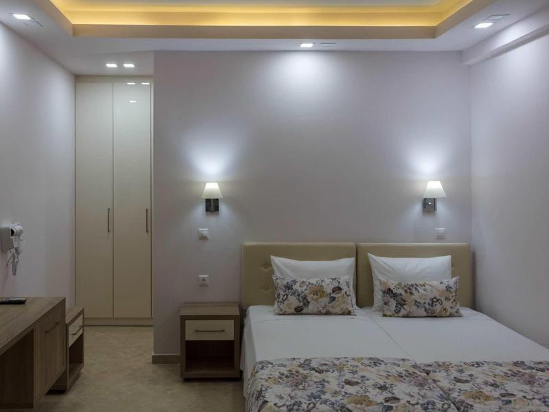 Chambre d'hôtel moderne avec lit double, table de chevet et éclairage de plafond indirect.