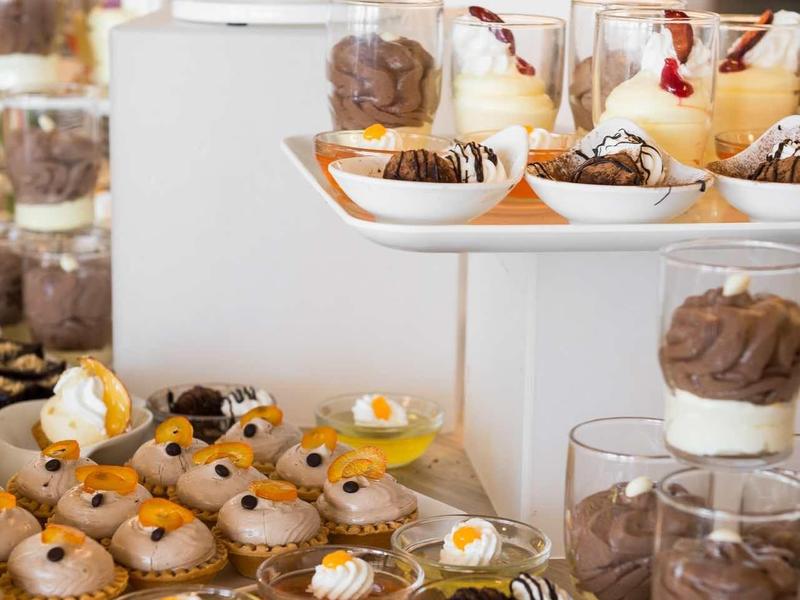 Vielzahl bunter Desserts und Kuchen auf mehrstufigen weißen Präsentationsplatten arrangiert.