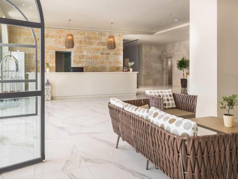 Heller, moderner Empfangsbereich mit gemütlichen, braunen Sofas, weißen Wänden und Marmorfußboden.