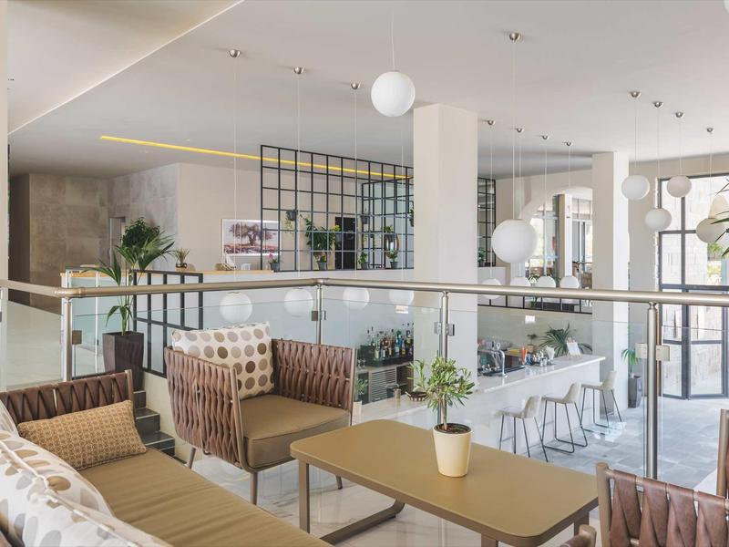 Helles, modernes Café mit gemütlichen Sitzbereichen, Pflanzen und Glasfronten für viel Tageslicht.