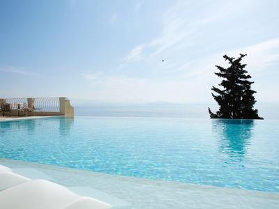 Piscina a sfioro con vista sul mare e una piattaforma alberata.