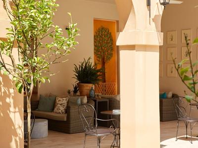 Accogliente terrazza aperta con area salotto e piante in tonalità calde di terracotta.