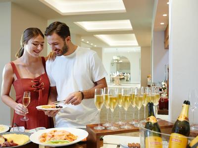 Para delektująca się napojami i jedzeniem przy bufecie w jasnym, nowoczesnym pokoju.