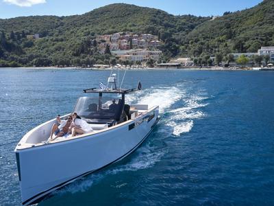 Lussuoso yacht bianco naviga su acqua blu davanti a una costa boscosa.