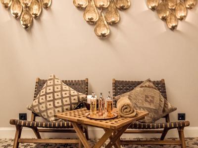 Przytulny kącik do siedzenia z dwoma krzesłami, poduszkami i drewnianym stolikiem z szachami pod dekoracjami na ścianie.