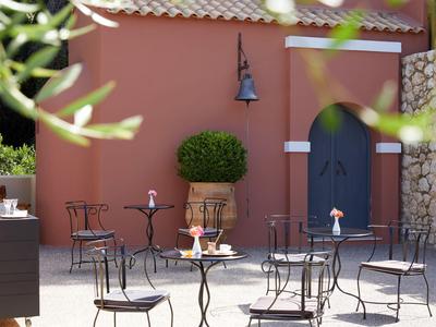Piccola area patio con tavoli e sedie davanti a un edificio rosso con porta blu.