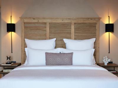 Nowoczesny pokój hotelowy z dużym białym łóżkiem, drewnianym zagłówkiem i lampami ściennymi