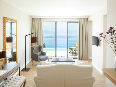 Jasny salon z widokiem na morze przez duże szklane okna w pokoju hotelowym.