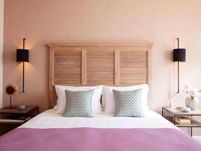 Przytulne podwójne łóżko z drewnianym zagłówkiem, białą pościelą, dwoma poduszkami i fioletowym kocem.