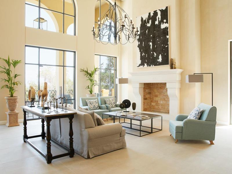 Jasny, nowoczesny salon hotelowy z dużymi oknami, kominkiem i stylowymi meblami.