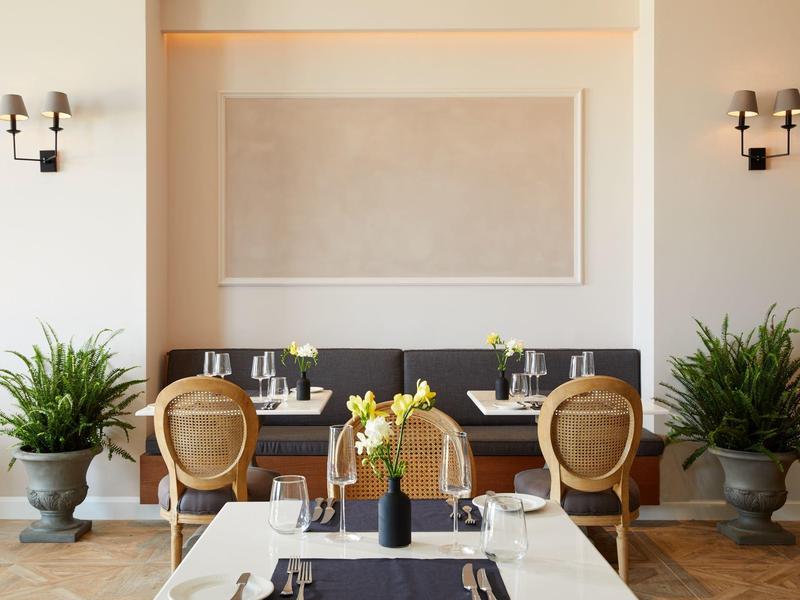 Elegancka część jadalna hotelu z nowocześnie udekorowanym stołem i roślinami w dużych donicach.