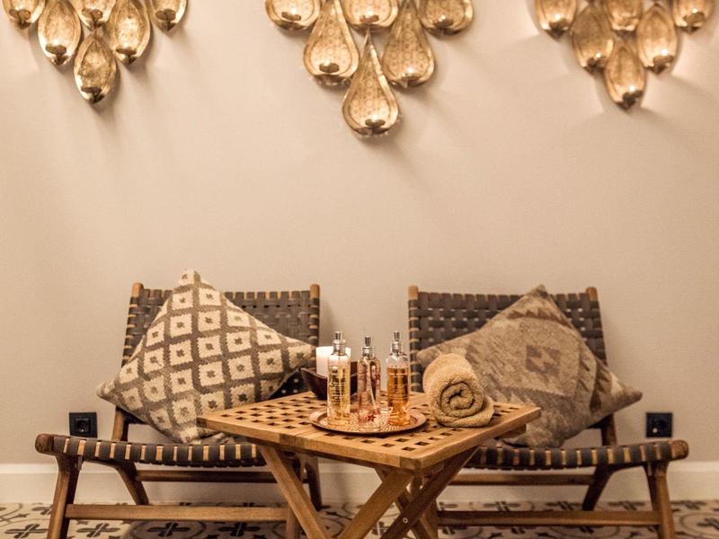 Przytulny kącik do siedzenia z dwoma krzesłami, poduszkami i drewnianym stolikiem z szachami pod dekoracjami na ścianie.