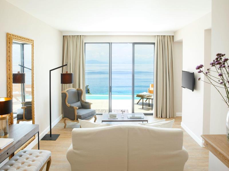 Jasny salon z widokiem na morze przez duże szklane okna w pokoju hotelowym.