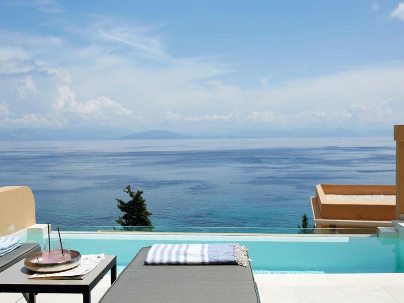 Widok na basen typu infinity z podanym tacą i morzem w tle pod pochmurnym niebem.