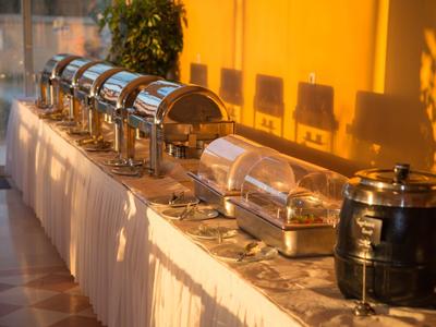 Buffetopstelling met meerdere warmhoudbakken en soepcontainer op een lange tafel met warm licht.