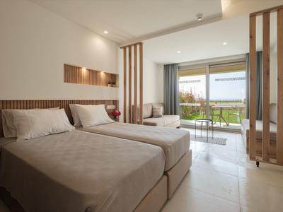 Moderne hotelkamer met twee bedden, houten accenten en balkon met uitzicht op tuin.