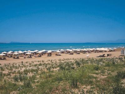 Spiaggia con lettini, ombrelloni e mare calmo e blu sullo sfondo.