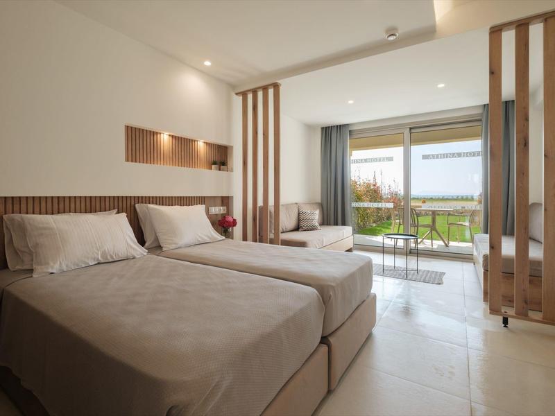 Moderne hotelkamer met twee bedden, houten accenten en balkon met uitzicht op tuin.