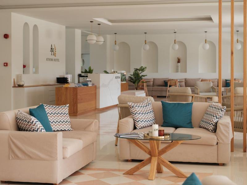 Ruime hotel lobby met beige banken, houten receptiebalie en moderne inrichting.