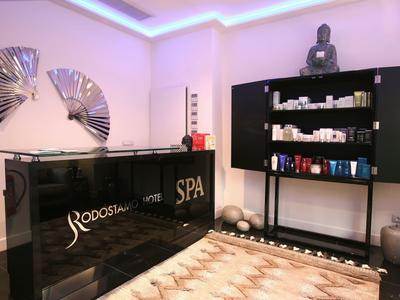 Moderner Spa-Empfang mit schwarzem Tresen, Regalen voller Produkte und hellen Wänden, dekoriert mit Figuren.