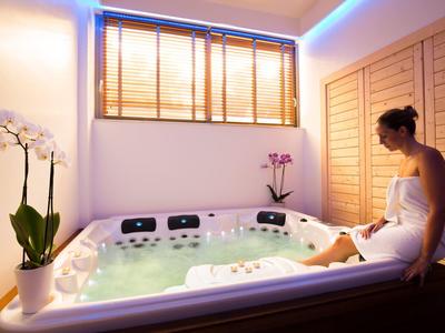 Moderner Whirlpool mit sprudelndem Wasser in hellem Raum, Pflanzen und weichem blauem Licht.