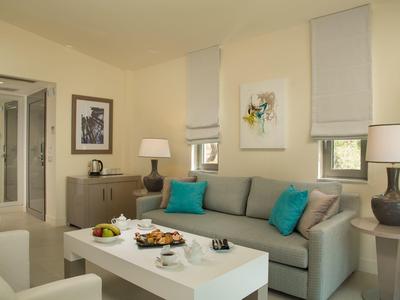 Helles Wohnzimmer mit grauem Sofa, blau-grauen Kissen, weißem Tisch und zwei dunkelgrauen Lampen.