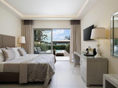 Modernes Schlafzimmer mit großem Bett, grauem Bettzeug, Schreibtisch und Terrasse mit Ausblick.