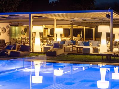 Osvětlená venkovní část hotelu s bazénem a útulnými posezeními v noci.