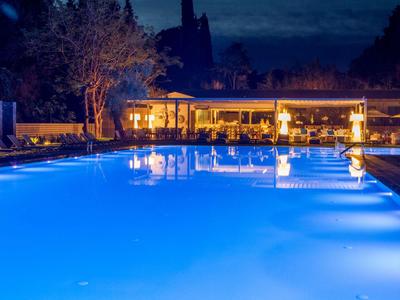 Jasně osvětlený bazén před útulným barem se sezením v noci