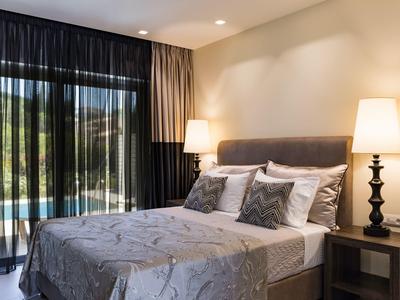 Modern eingerichtetes Schlafzimmer mit Doppelbett, grauer Bettwäsche, Nachttischen und Lampen.