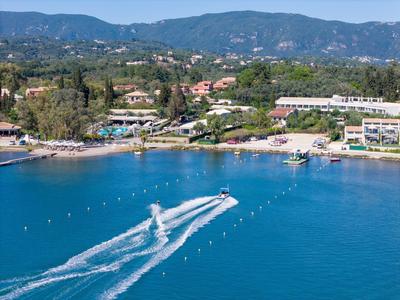Klares blaues Meer mit zwei Jetskis, die Wellen vor einer grünen Küstenlandschaft ziehen.