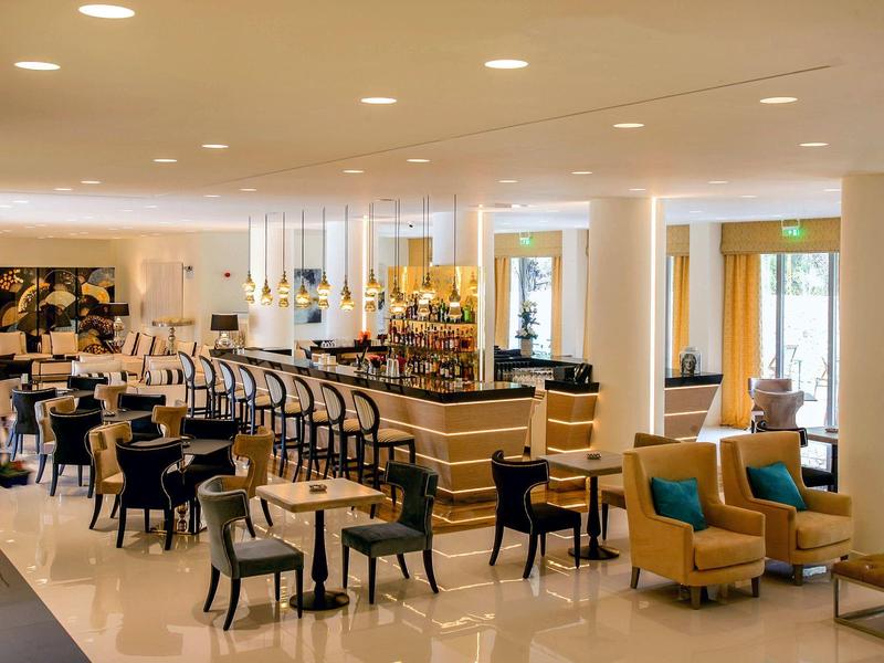 Elegantes Café mit Tischen, Stühlen und gemütlichen Sesseln in hellem, modernem Ambiente.