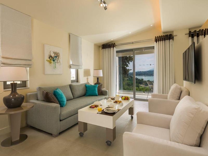 Helles Wohnzimmer mit graßem Fenster, gemütlicher Couch, weißen Sesseln und moderner Dekoration.